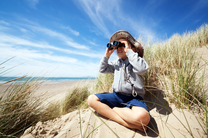 A little boy looks out binoculars