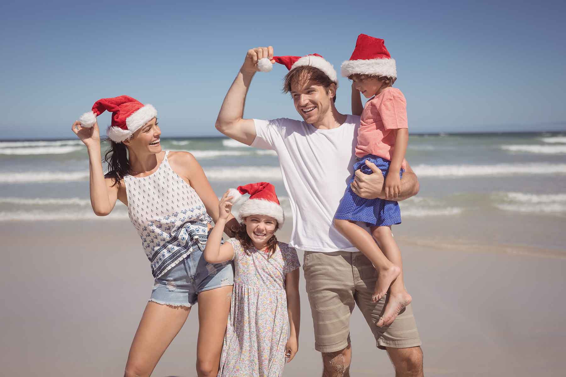 Family of four with Santa hats on the beach