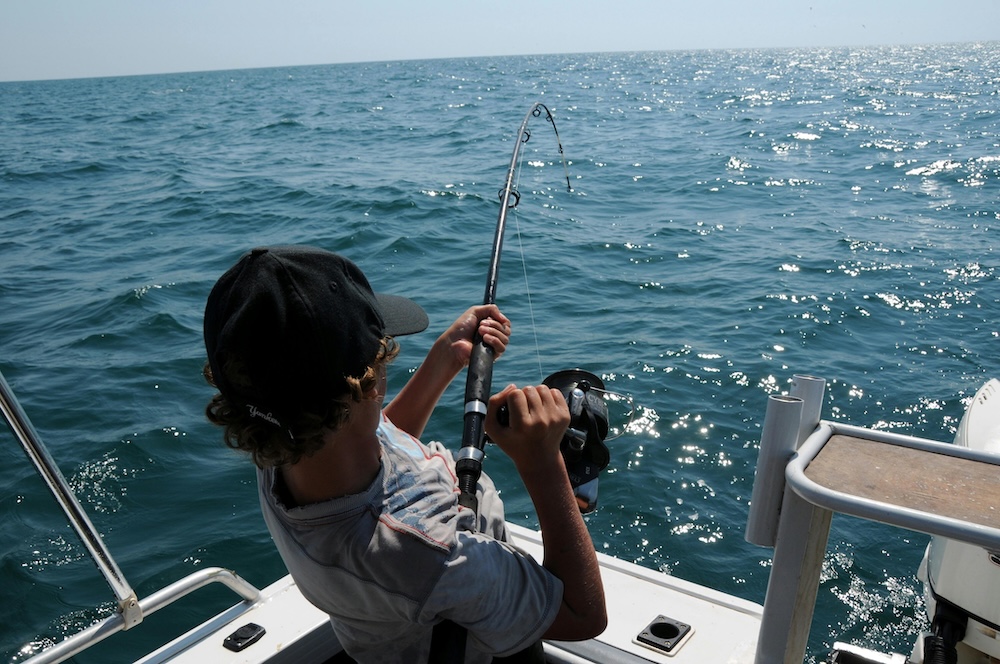 Boy catching a fish from a boat